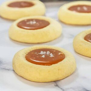 Five dulce de leche cookies on a marble background.